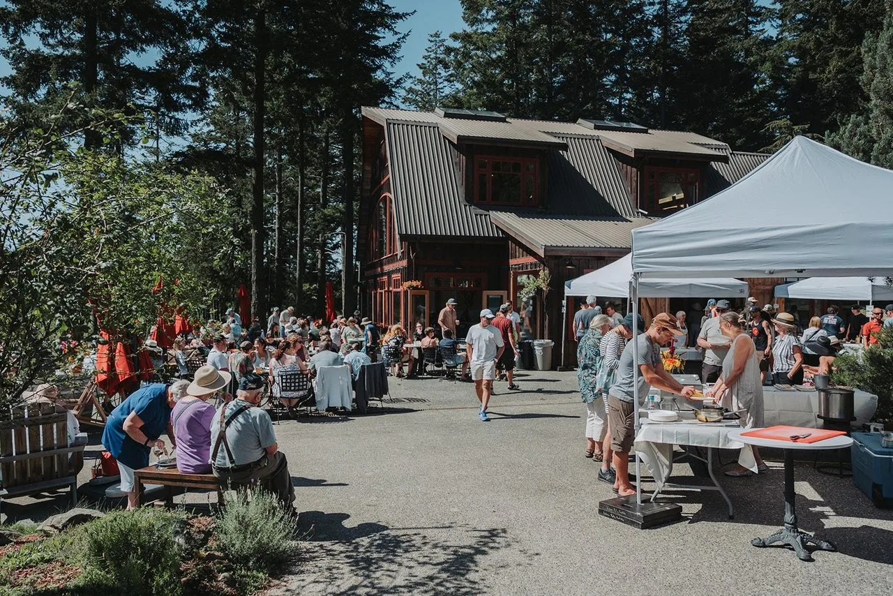 many people gather outside a building on saturna island for a festival