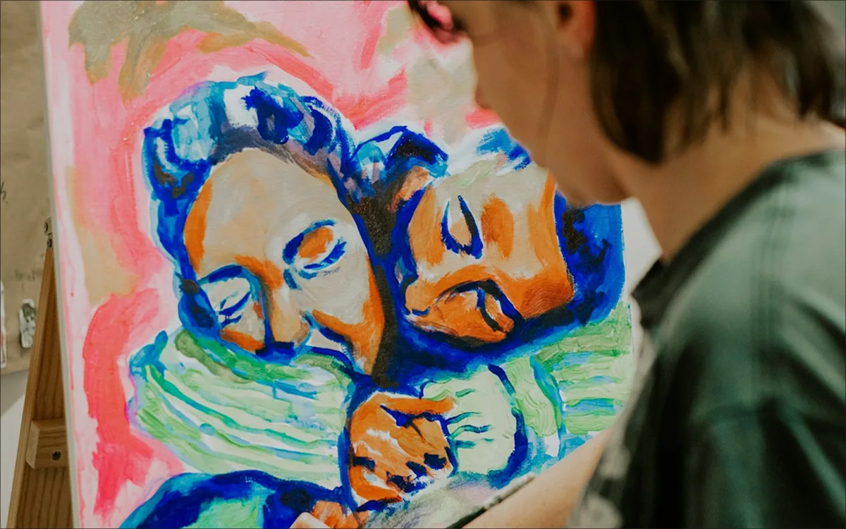 someone painting a picture of 2 individuals embraacing